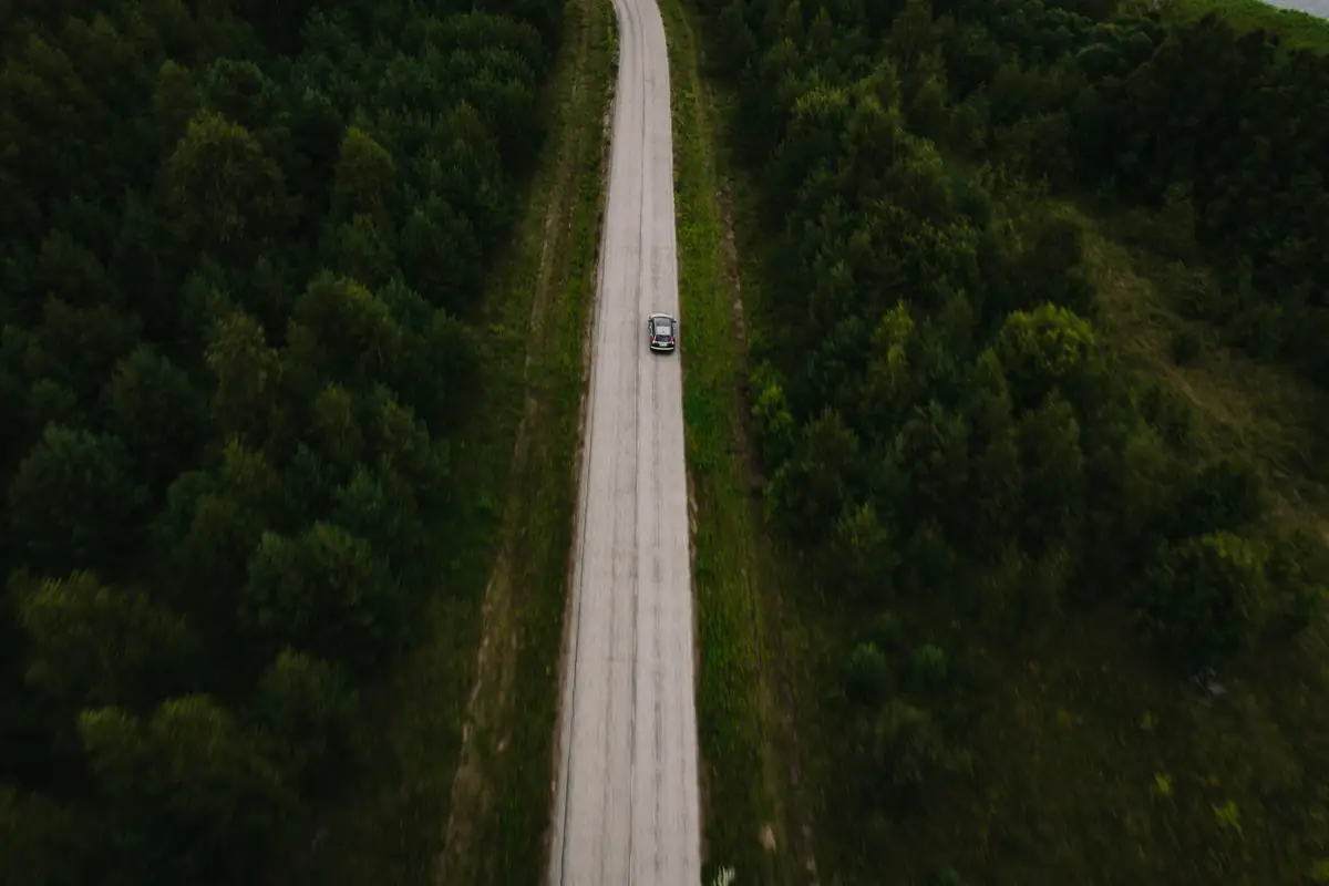 An aerial view of a straight road through green woodland